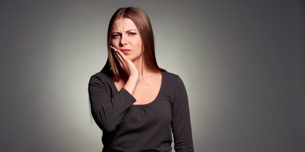 sad woman have a toothache. studio shot over dark background